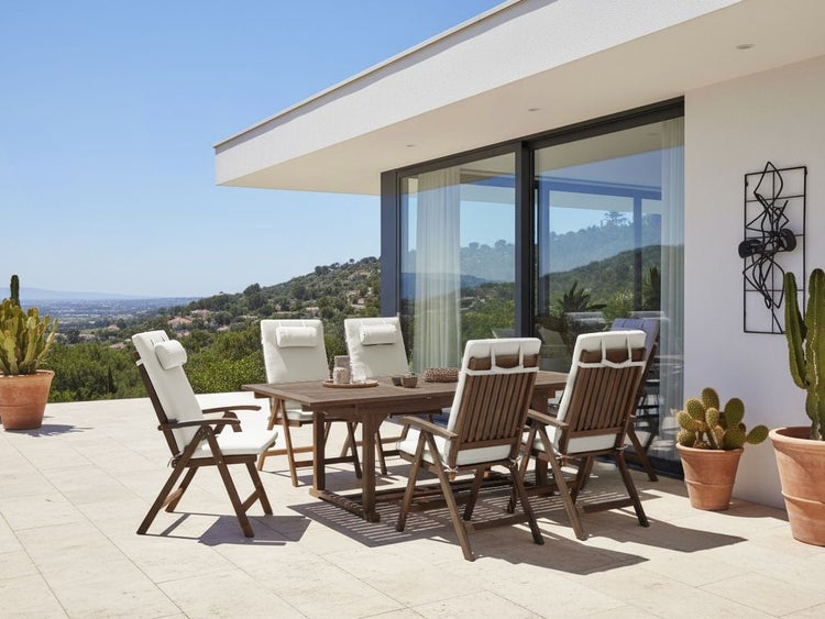 Helle, moderne Terrasse mit Garten-Essgruppe aus Holz, bestehend aus rechteckigem Tisch und Klappstühlen mit Auflagen.