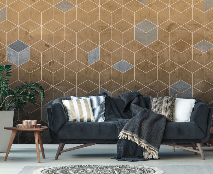 Modernes Wohnzimmer mit einer Fototapete in geometrischem Hexagon-Design. Dunkelgraues Sofa mit Dekokissen, Decke, Beistelltisch und Zimmerpflanze.