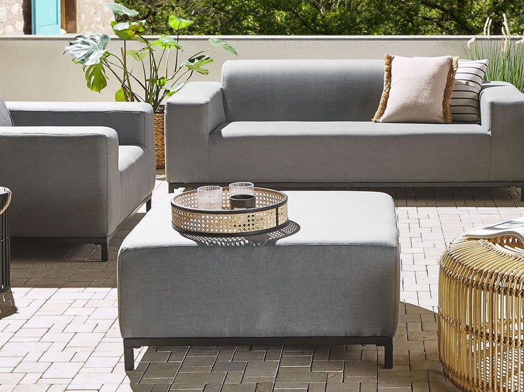 Terrassenszene mit grauem Sofa, Sessel und Hocker mit Tablett