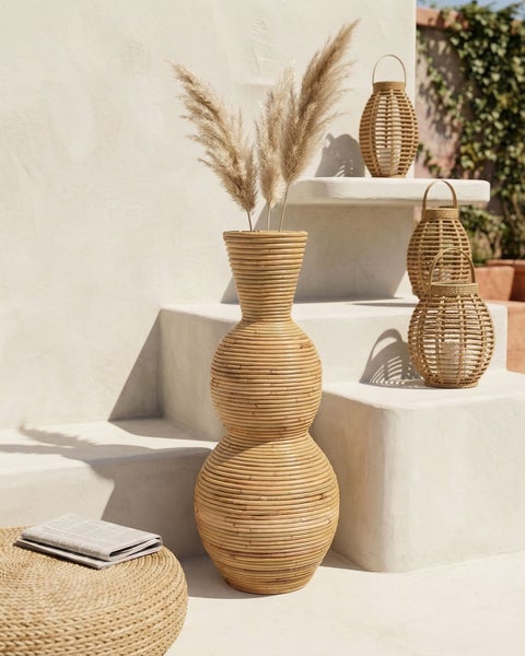 Große Bodenvase aus Bambus mit Pampasgras, dekorative Laternen und ein Hocker in einer hellen, minimalistischen Umgebung.