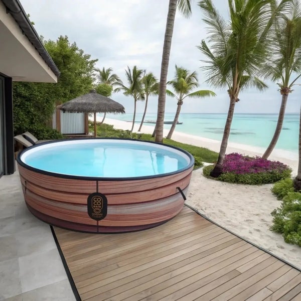 Runder Whirlpool in Holzoptik auf einer Holzterrasse in einer tropischen Strandszene mit Palmen.