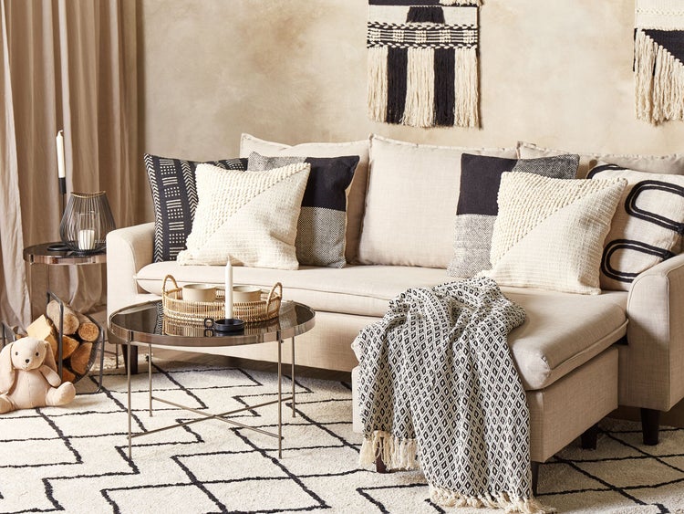 Wohnzimmer mit Sofa, Kissen, Decke, Teppich und Beistelltisch