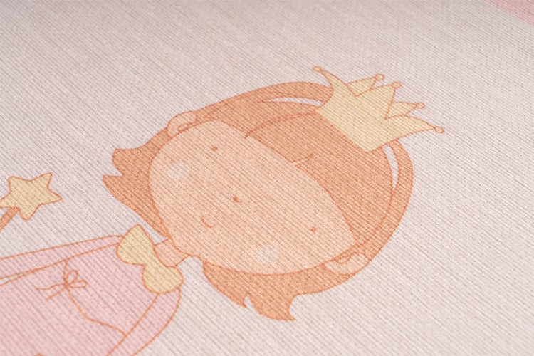 Nahaufnahme eines Kinderteppichs mit Prinzessinnen-Motiv, Krone und Zauberstab auf strukturierter Oberfläche.