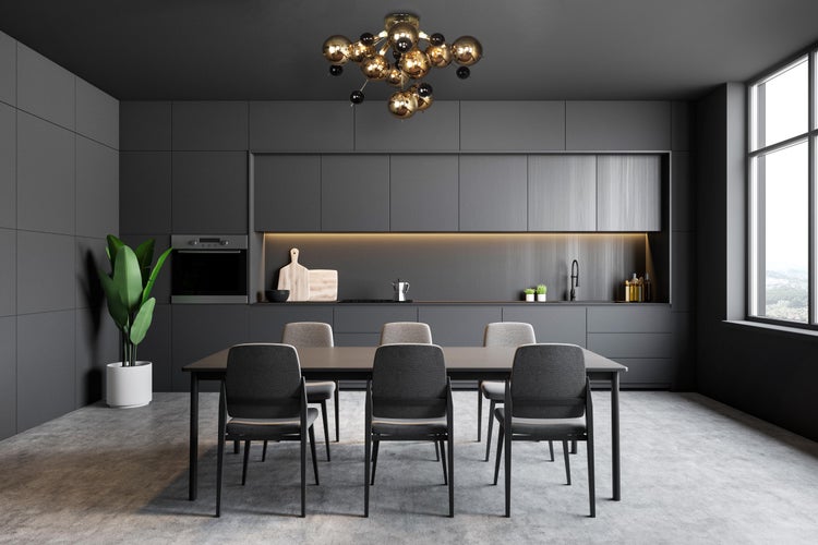 Moderne Küche mit Esstisch, Stühlen, Einbauschränken und Zimmerpflanze.
