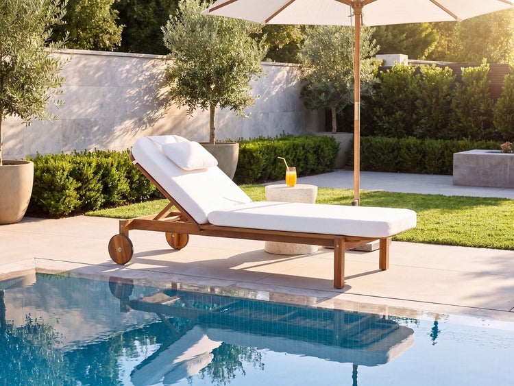 Gartenliege aus Holz mit Polsterauflage am Poolrand mit Sonnenschirm und Beistelltisch in einer sonnigen Gartenlandschaft.