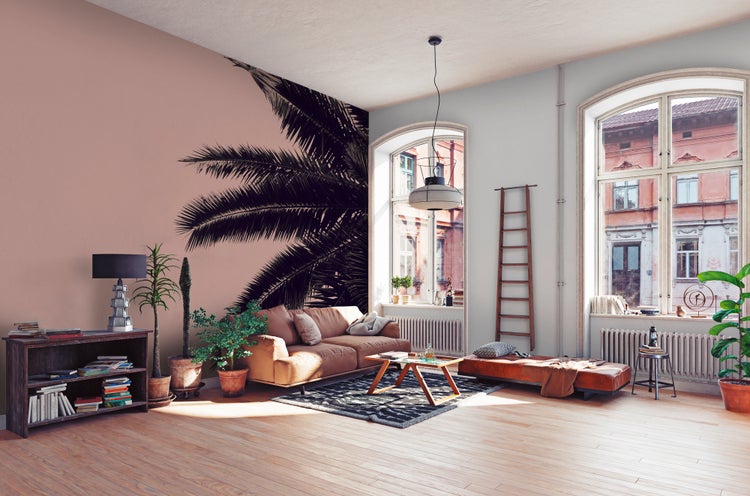Modernes Wohnzimmer mit Fototapete mit Palmenwedeln, Ledersofa, Holztisch und großen Bogenfenstern auf Parkettboden.