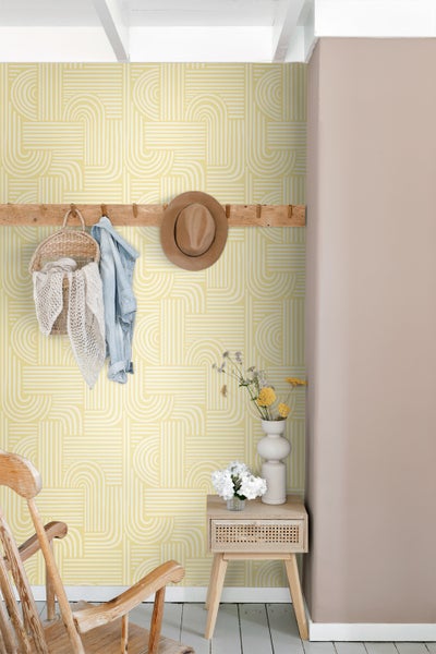 Wohnraum mit geometrischer Tapete, Kleiderhakenleiste mit Accessoires und Beistelltisch mit Blumenvasen