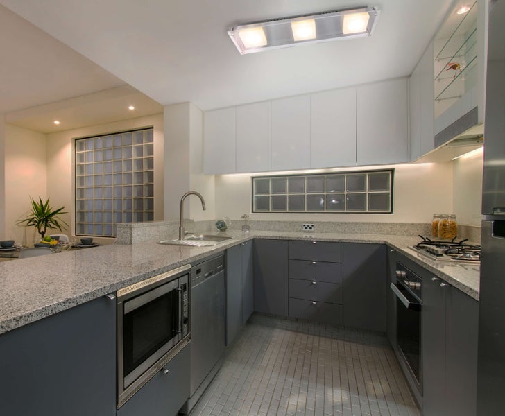 Helle Küche mit grauen Schränken, Granitoberflächen und Edelstahlgeräten.