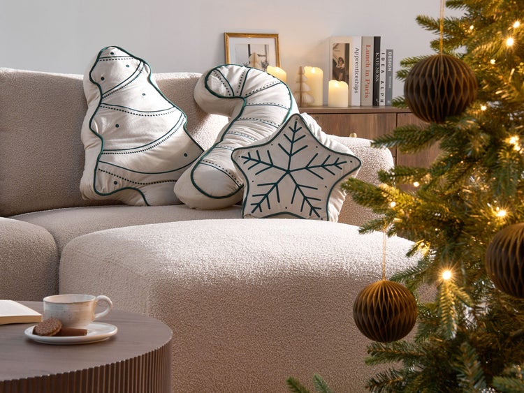 Dekorative Weihnachtskissen in Form eines Tannenbaums, einer Zuckerstange und eines Schneeflockensterns auf einem Sofa