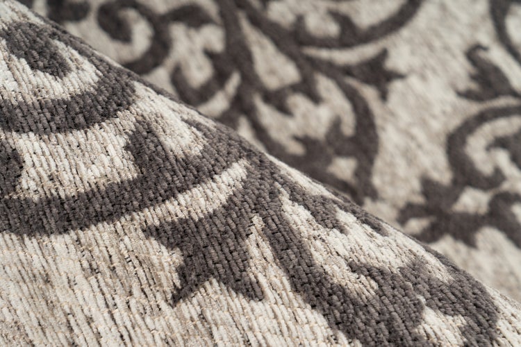 Nahaufnahme eines gewebten Teppichs mit grau-beigem Ornamentmuster.