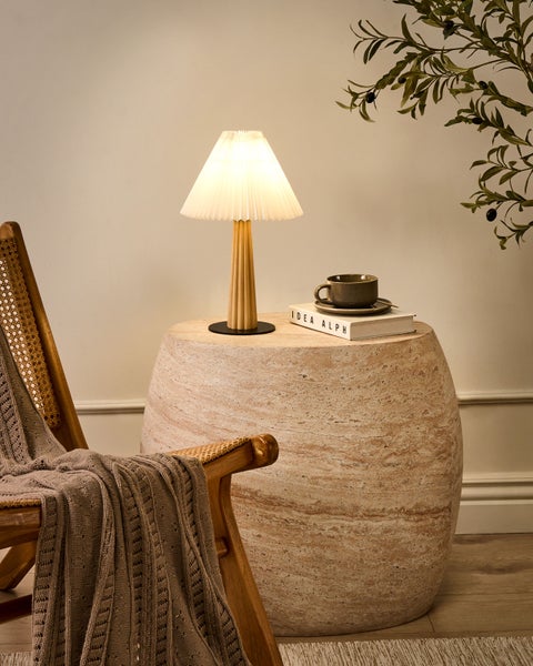 Szene mit Sessel, Decke, Beistelltisch mit Lampe, Tasse, Untertasse und Buch