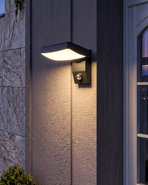 Moderne LED-Außenwandleuchte mit Bewegungsmelder, an einer Hauswand montiert, strahlt warmes Licht nach unten ab.