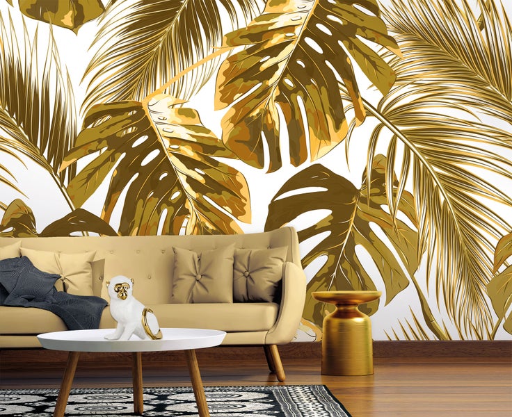 Modernes Wohnzimmer mit einer Fototapete mit großen goldenen Monstera- und Palmblättern, einem beigen Sofa und einem goldenen Beistelltisch.