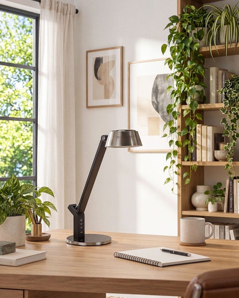 Moderne Schreibtischleuchte mit verstellbarem Arm auf einem Holztisch in einem eingerichteten Arbeitszimmer.