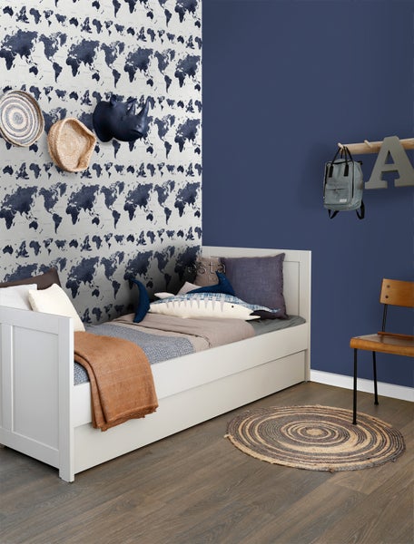 Kinderzimmer mit weißem Bett, Weltkarten-Tapete und rundem Teppich