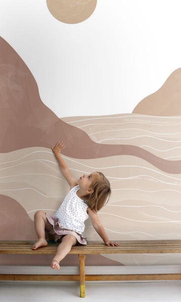 Kind sitzt auf einer Bank vor einer Wand mit abstraktem Design