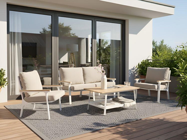 Terrasse mit Sitzgruppe, bestehend aus Sofa, Sesseln und Tisch auf einem gemusterten Teppich.