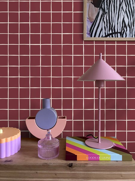 Dekorative Szene mit Lampe, Dekorationsartikeln und Buch auf einem Holztisch vor einer Fliesenwand