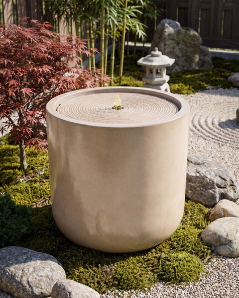 Zylindrischer Gartenbrunnen in einem organisierten Zen-Garten mit Moos, Natursteinen, Bambus und einem japanischen Ahorn.