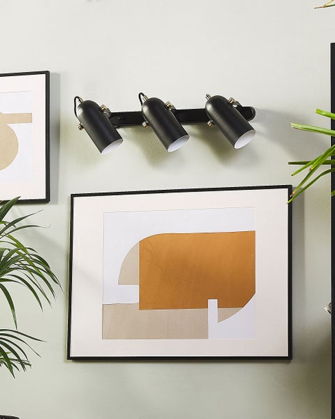 Wandspot mit drei Leuchten neben gerahmten Bildern