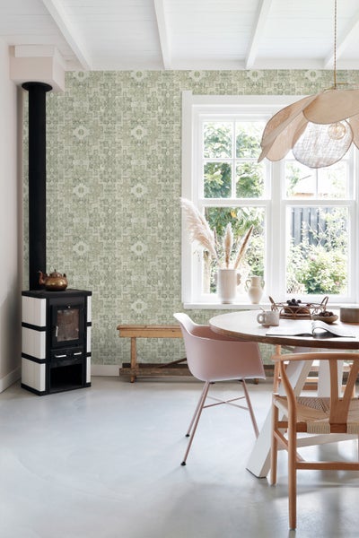 Heller Raum mit gemusterter Tapete, Ofen, Tisch und Stühlen.