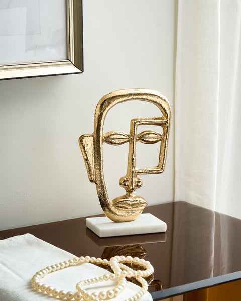 Dekorative goldfarbene Gesichtsskulptur auf einem Tisch