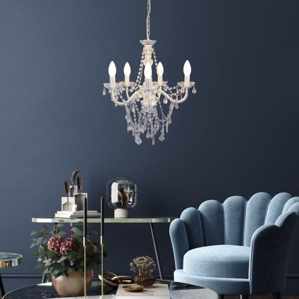 Einrichtung mit Kristalllüster, Sessel und Beistelltischen in einem hellen Wohnzimmer.