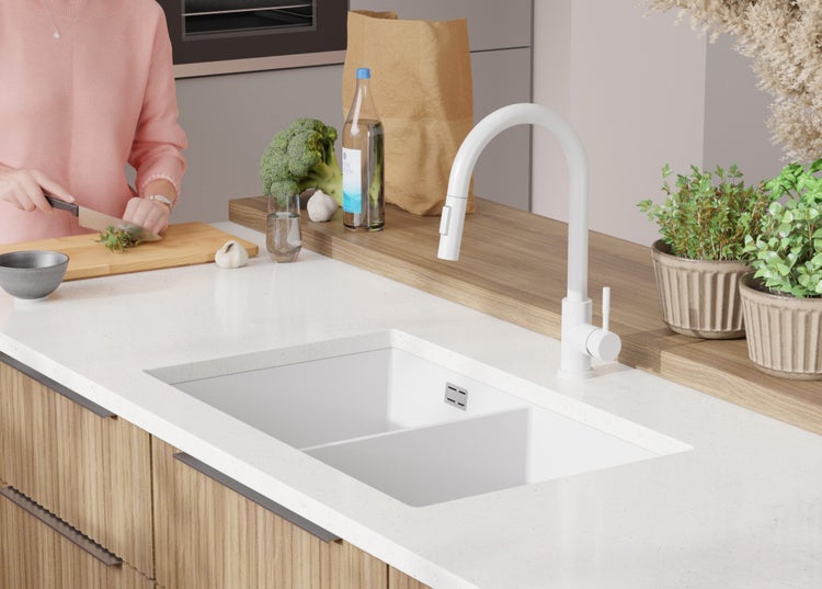 Moderne Küchenszene mit Spüle, Armatur und Person beim Gemüseschneiden