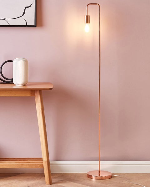 Stehlampe aus Metall neben einem Holztisch mit einer Vase und einem Bild