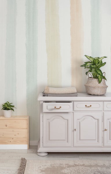 Einrichtung mit Kommode, Dekoration und gestreifter Tapete für ein helles, organisiertes Ambiente.