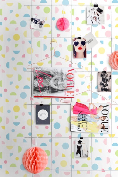 Vliestapete mit geometrischem Muster aus Kreisen und Halbkreisen in Pastelltönen, dekoriert mit Gitterwand, Magazinen und Wabenbällen.