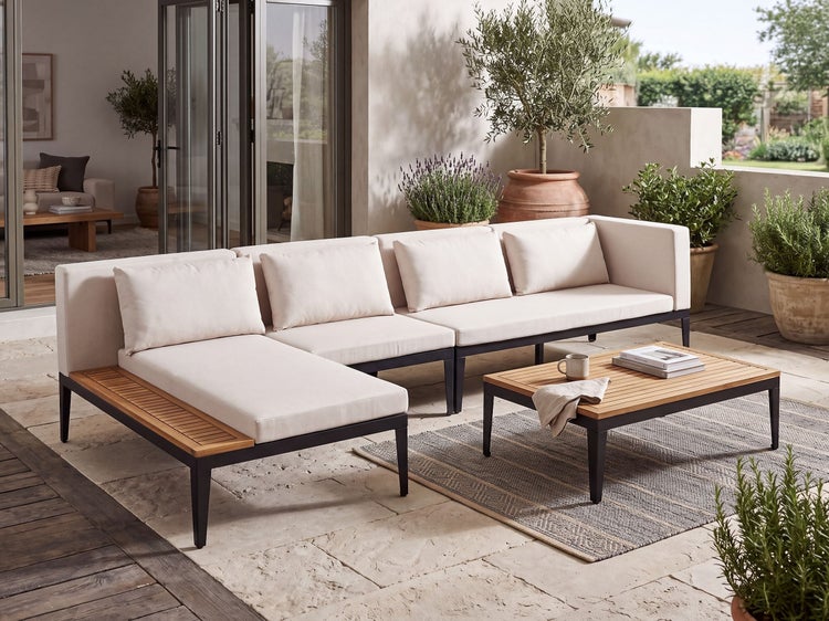 Moderne Loungegarnitur mit Ecksofa und Couchtisch auf einer Terrasse, mit Holz- und Metall-Elementen sowie hellen Sitzkissen.