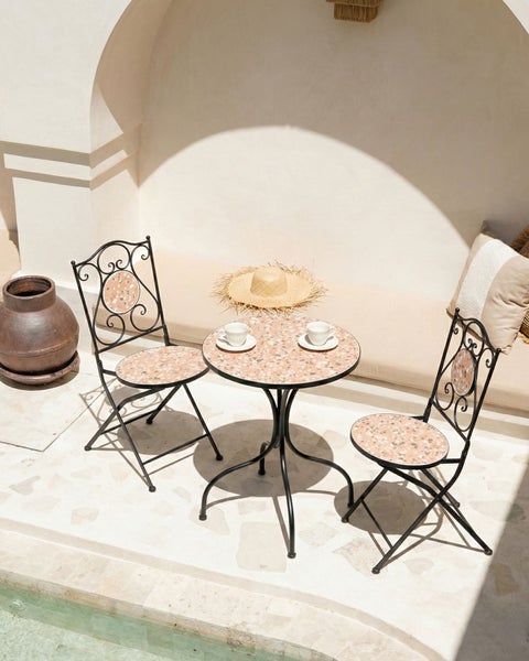 Gartenszene mit Tisch und zwei Stühlen aus Metall und Mosaik sowie Dekorationen im Außenbereich