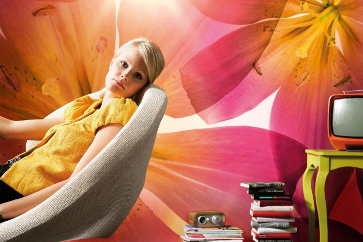 Frau entspannt in einem Sessel vor einer Fototapete mit Blumenmuster.