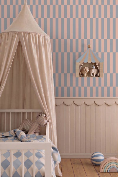 Kinderzimmer mit geometrischer Tapete, Wandpaneelen mit Wellenkante, Gitterbett mit Stoffhimmel und einem Wandregal im Zirkusdesign.