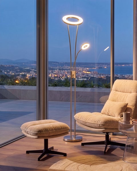 Moderne LED Deckenfluter Stehlampe mit Leseleuchte in einem Wohnzimmer mit Blick auf eine Stadt bei Abenddämmerung.