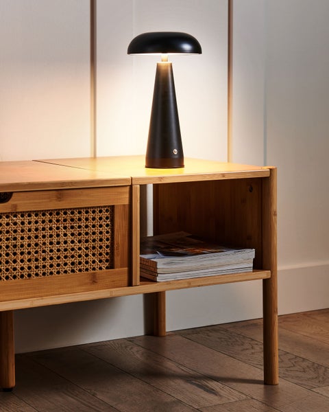 Moderne schwarze Tischleuchte in Pilzform auf einem Beistelltisch aus Bambus mit Wiener Geflecht.