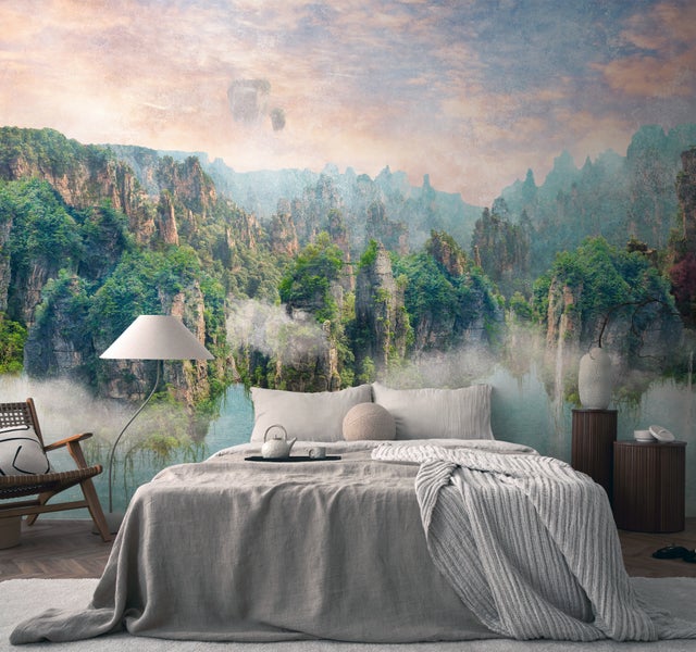 Fototapete mit Berglandschaft und Nebel in einem modern eingerichteten Schlafzimmer mit grauem Bett und Holzakzenten.