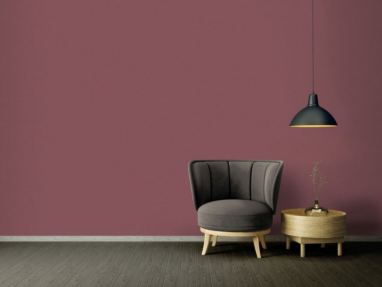 Wohnzimmer mit Sessel, Beistelltisch und Hängelampe vor einer farbigen Wand