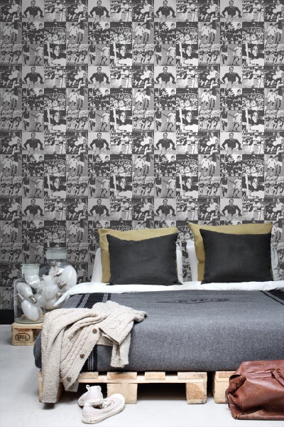 Schlafzimmer mit Bett auf Holzpalette und Tapete mit Sportmotiven