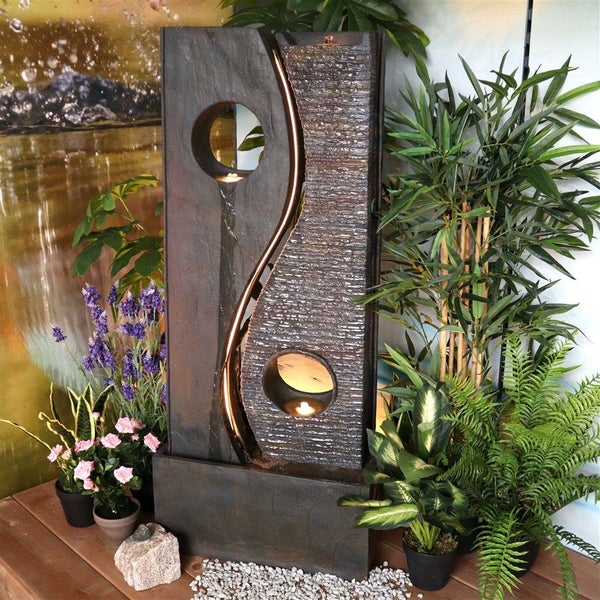 Dekorativer Zimmerbrunnen aus Stein mit zwei runden Öffnungen und Pflanzen