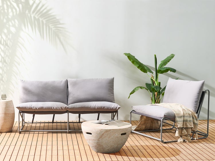 Gartenszene mit einem Sofa, einem Sessel, einem Tisch und einer Zimmerpflanze auf einem Holzboden