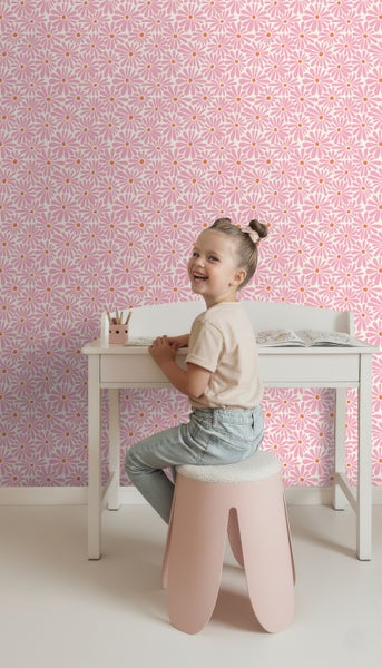 Helles Kinderzimmer mit Schreibtisch, Hocker und Tapete mit Gänseblümchenmuster