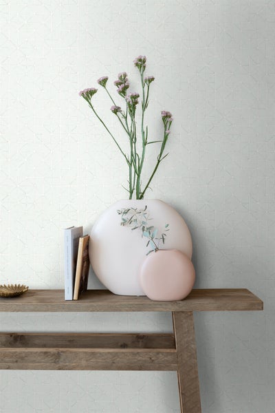 Wandgestaltung mit geometrischer Tapete, Holztisch, Vasen und Büchern für ein stilvolles Interieur