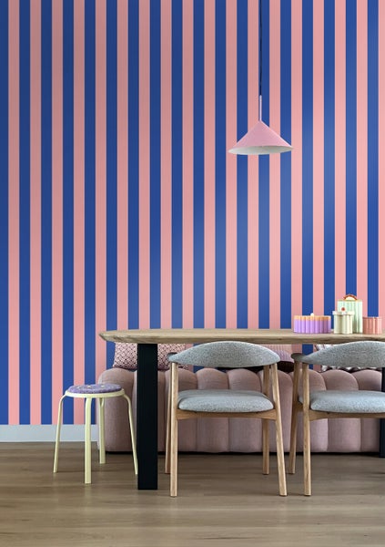 Esszimmer mit Esstisch, Stühlen, Hocker, Lampe und Tapete mit Streifenmuster
