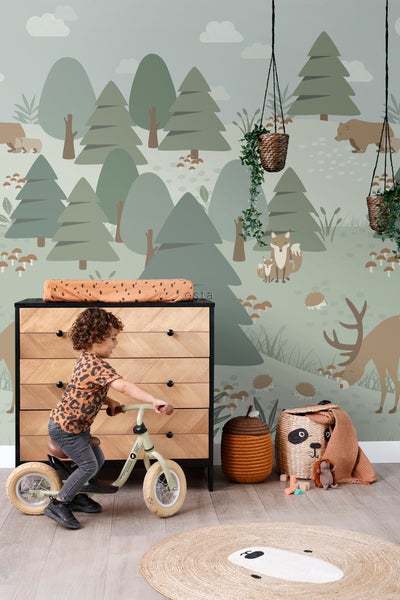 Kinderzimmer mit Kind auf Laufrad, Kommode und Waldtapete