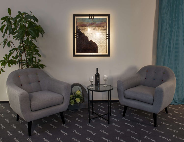 Dekoratives Interieur mit zwei Sesseln, einem Beistelltisch mit Getränken und einem beleuchteten Wandbild