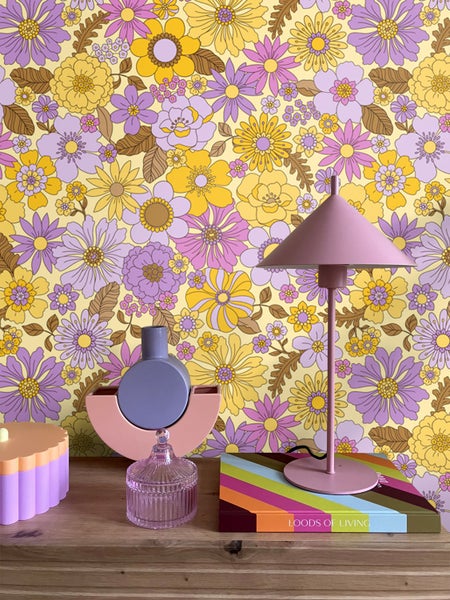 Dekorative Szene mit Lampe, Vasen und Buch vor einer floralen Tapete