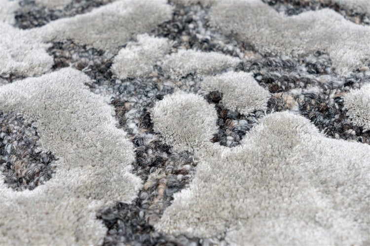 Nahaufnahme eines Teppichs in Grau und Silber mit Hoch-Tief-Struktur und abstraktem organischem Muster.