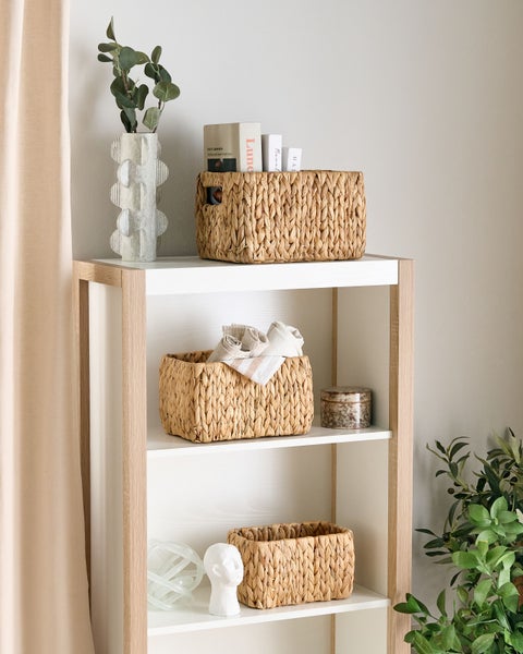 Regal mit drei Ebenen, dekoriert mit Weidenkörben und dekorativen Elementen.